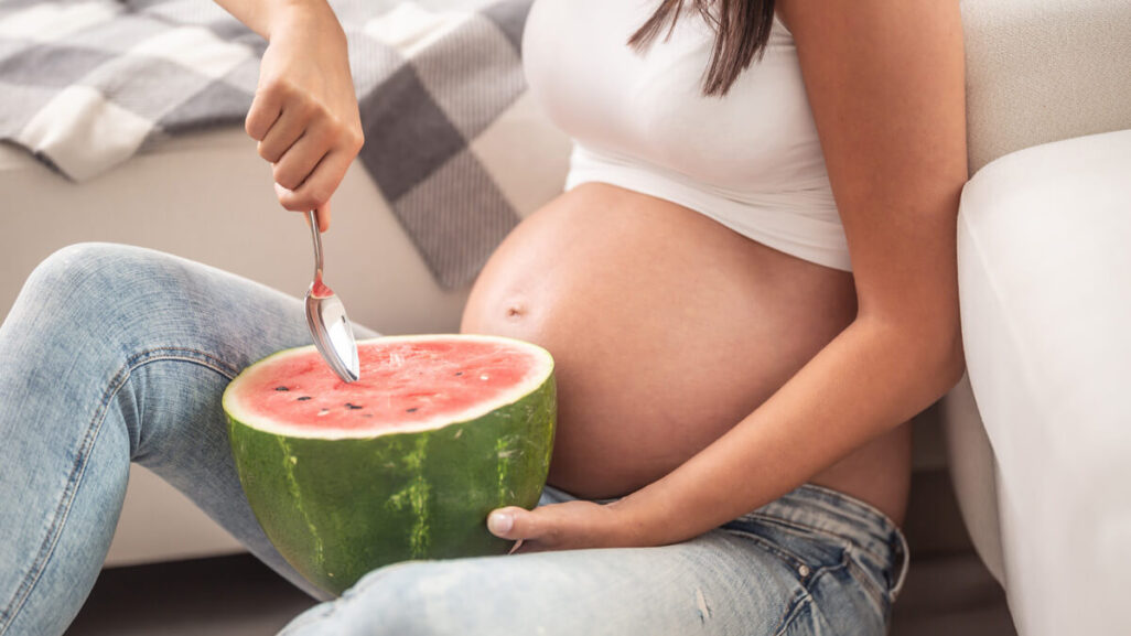 Schwangere Frau isst eine Wassermelone.