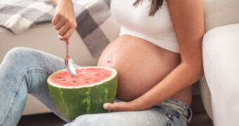 Schwangere Frau isst eine Wassermelone.