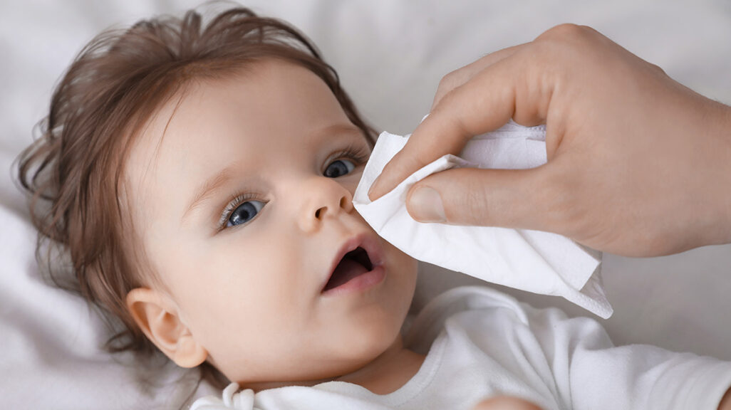 Vater putzt Babys Nase mit dem Taschentuch ab