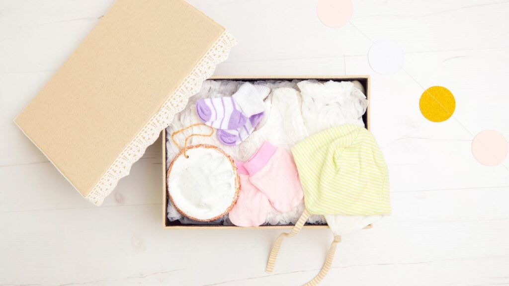 Eine Babybox mit Söckchen, Mützchen und Handabdruck