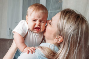 Mutter versucht mit ihrem weinenden Baby zu kuscheln.