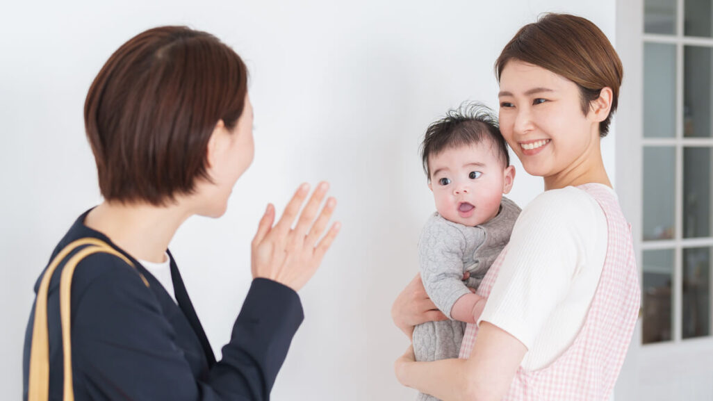 Mutter verabschiedet ihr Baby, das auf dem Arm einer anderen Frau ist.