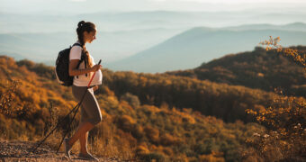 Schwangere Frau wandert mit Wanderstöcken durch die Berge