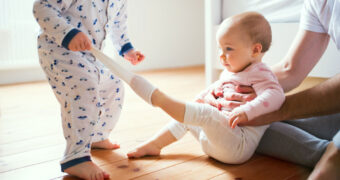 Kleinkind zieht einem Baby die Socken aus.