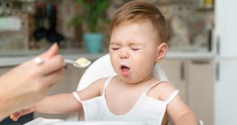 Baby wird gefüttert und verzieht angeekelt das Gesicht