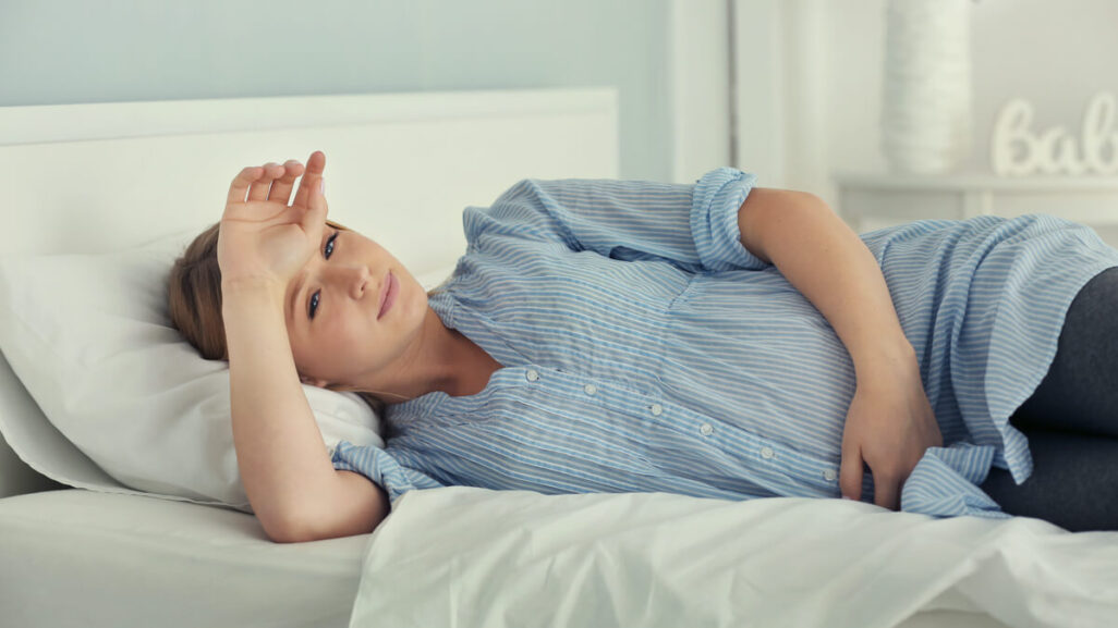 Schwangere liegt nachdenklich im Bett