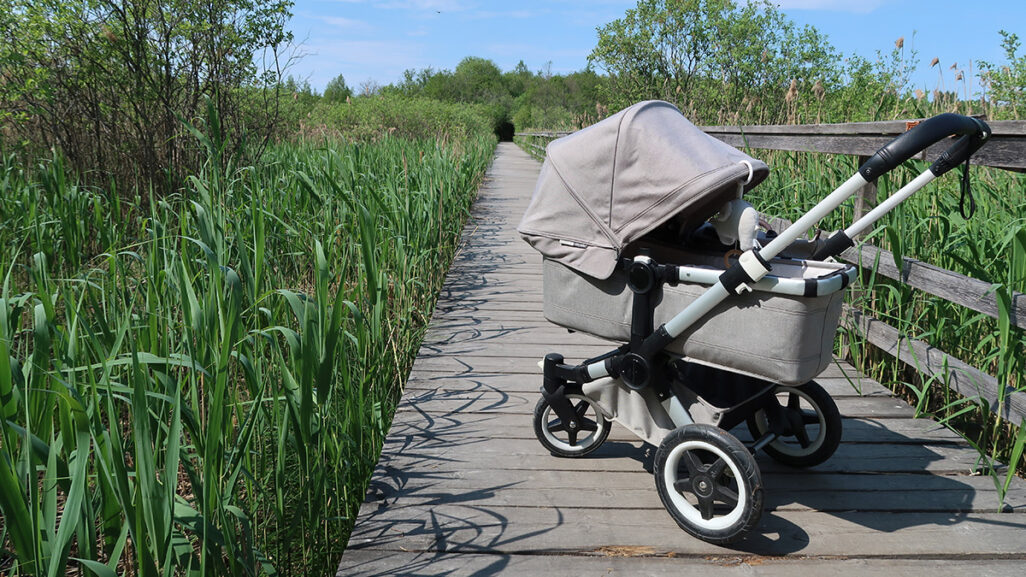 Kinderwagen steht am See in der prallen Sonne mit voll heruntergeklapptem Verdeck